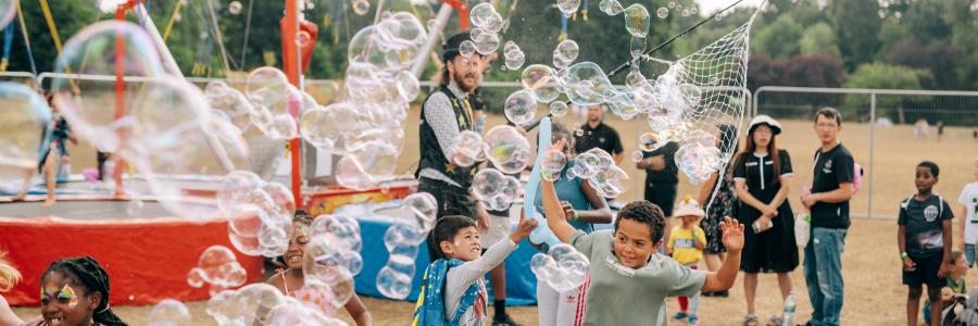 A group of children enjoy bursting a cloud of bubbles