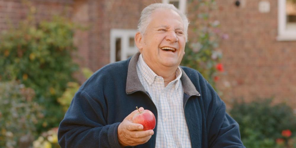Phoenix resident Peter Lewis standing in his garden holding an apple that was grown there